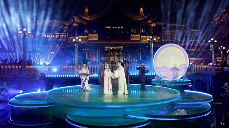 Yuyuan Garden’da gece, ışıklı sahnede geleneksel kostümlü sanatçılar müzik performansı sergiliyor