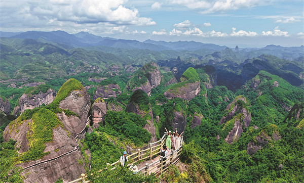 Zhangjiajie'yi gösteren yemyeşil kayalıklar ve ziyaretçilerin bulunduğu ahşap yürüyüş platformu