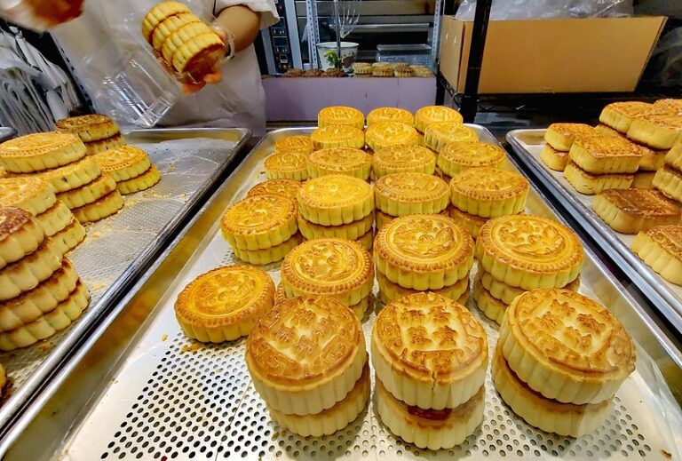 Tezgâhta farklı boyut ve desenlerde altın renkli mooncake’ler tepsiler üzerinde sergileniyor
