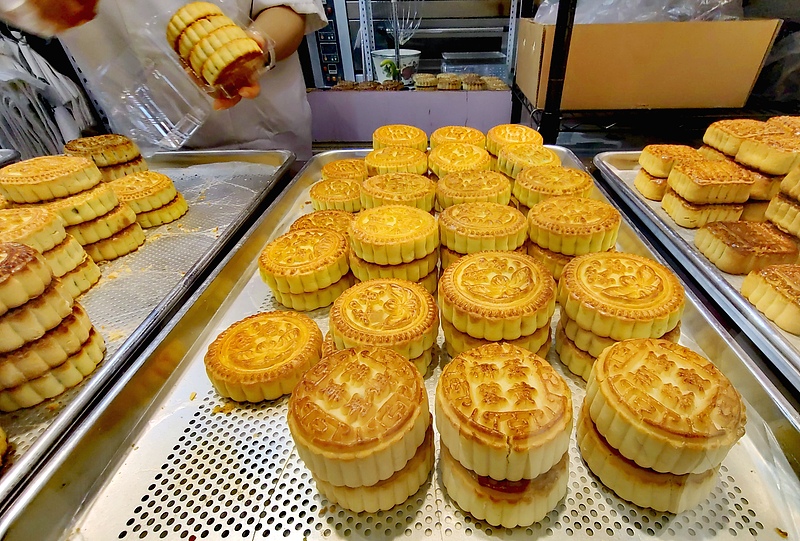 Tezgâhta farklı boyut ve desenlerde altın renkli mooncake’ler tepsiler üzerinde sergileniyor