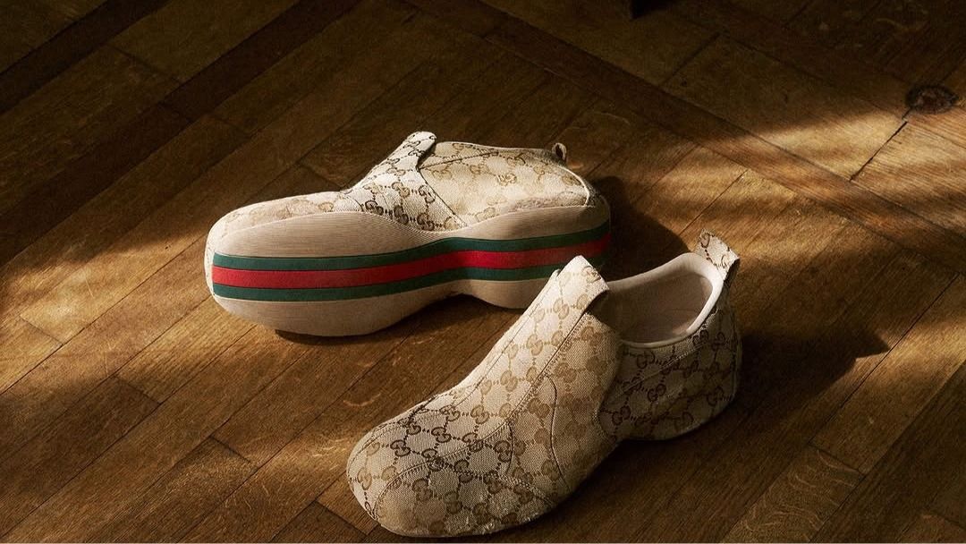 Gucci monogram desenli spor ayakkabılar ahşap zeminde, farklı bir tasarım detayıyla görülüyor