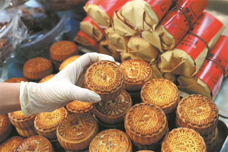 Eldivenli kişinin tezgâhta geleneksel mooncake'leri alıp gösterdiği yakın çekim fotoğrafı