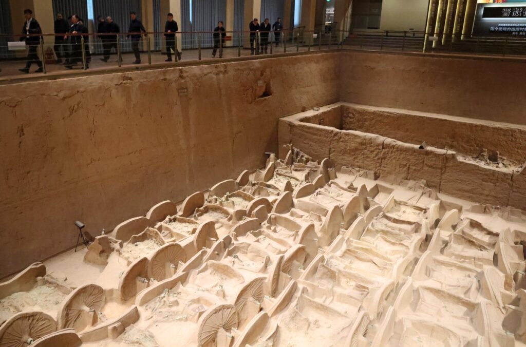 Müze salonunda sergilenen geniş arkeolojik kazı alanı ve üst galeride ziyaretçiler görülüyor