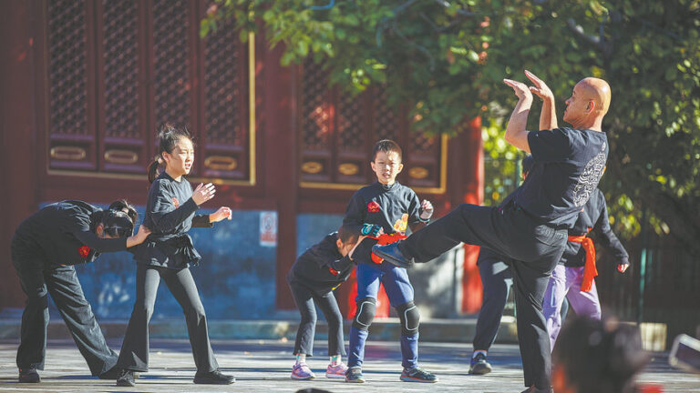 Beijing’de açık havada bir usta, çocuklara aslan dansı hareketlerini gösteriyor