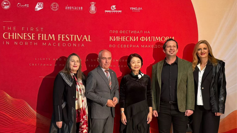 Kırmızı festival panosu önünde Çin Film Festivali açılışına katılan beş kişi görülüyor