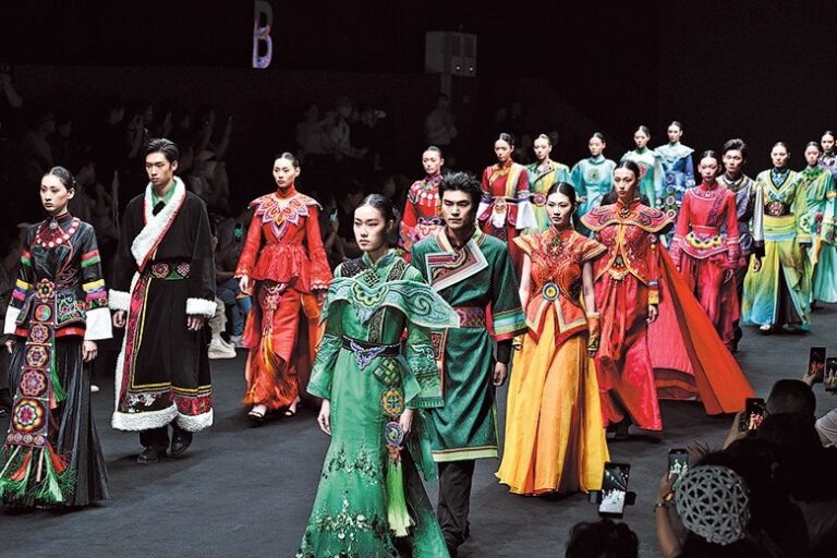 Renkli geleneksel kostümler giyen sanatçılar sahnede toplu performans sergiliyor